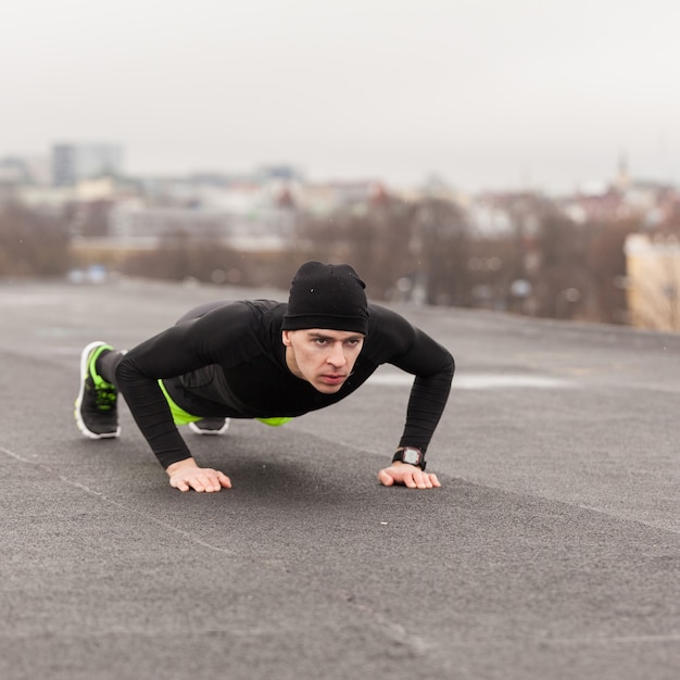 Człowiek robi push up na dachu