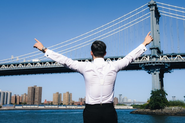 Człowiek rozprzestrzenia się ręce, stojąc przed dużym mostem