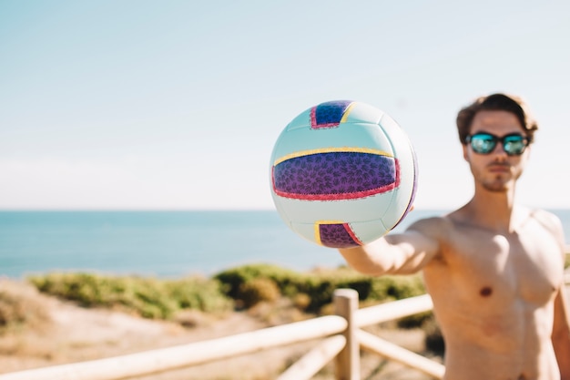 Człowiek trzyma siatkówkę na plaży