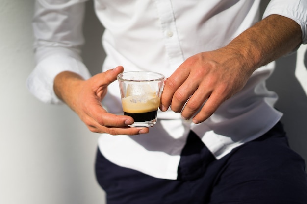 człowiek w białej koszuli pije kawę na zewnątrz w lecie