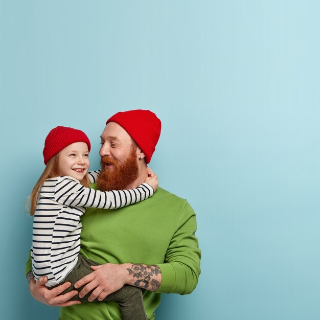 Człowiek z brodą imbir na sobie kolorowe ubrania i trzymając córkę
