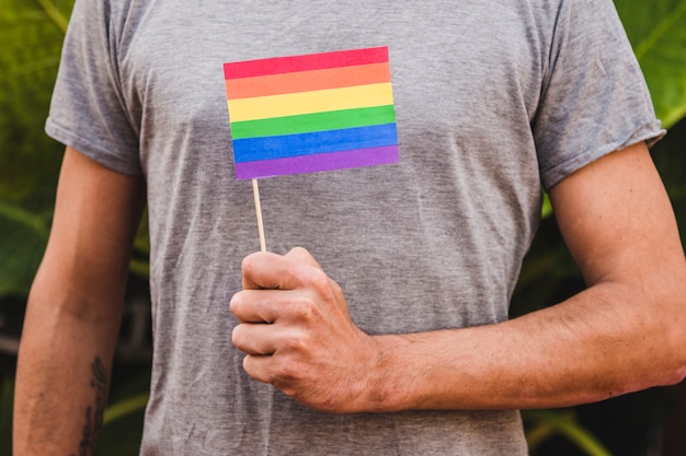 Człowiek z flagą w kolorach LGBT w ręku