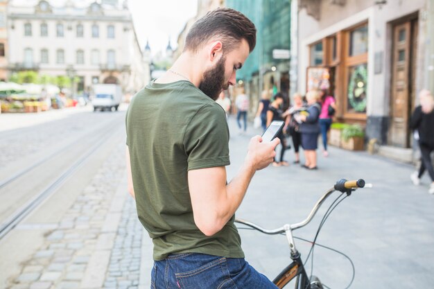 Człowiek z jego rower patrząc na ekran telefonu komórkowego