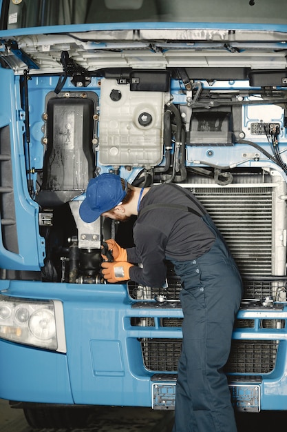 Bezpłatne zdjęcie człowiek z narzędziami do ciężarówki. pracownik w mundurze. wadliwa ciężarówka