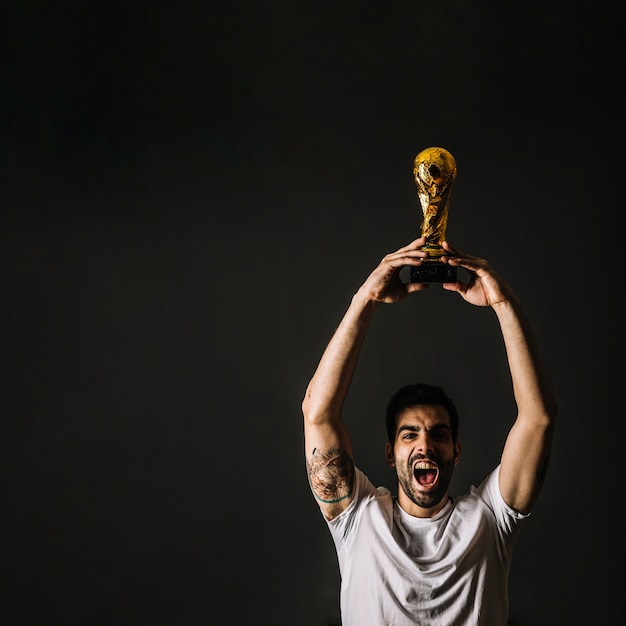 Bezpłatne zdjęcie człowiek z trofeum fifa świętuje zwycięstwo