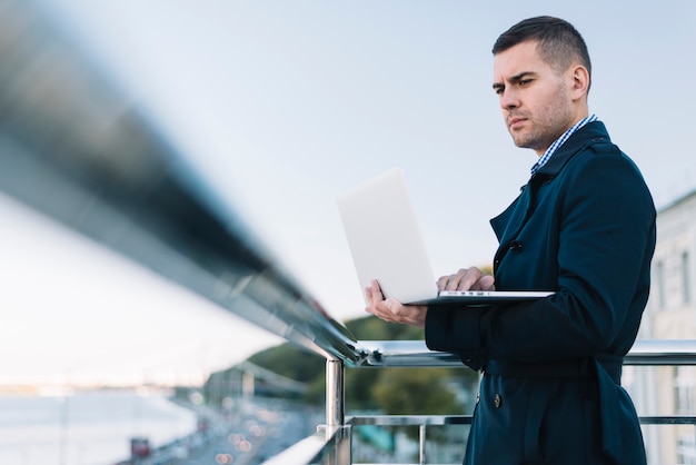 Bezpłatne zdjęcie człowiek za pomocą laptopa w środowisku miejskim