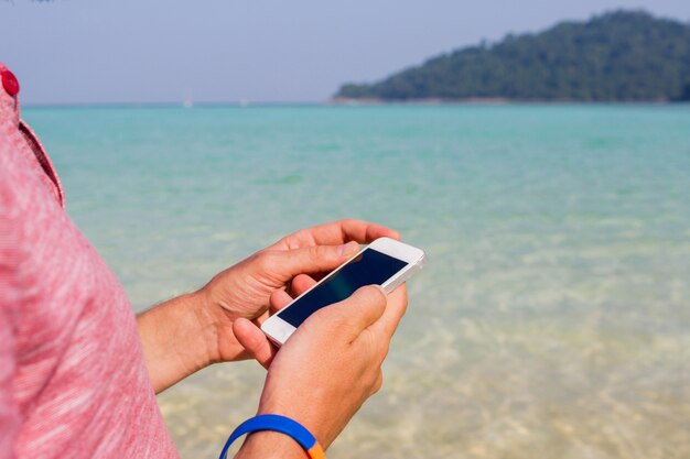 Człowiek za pomocą telefonu komórkowego na plaży