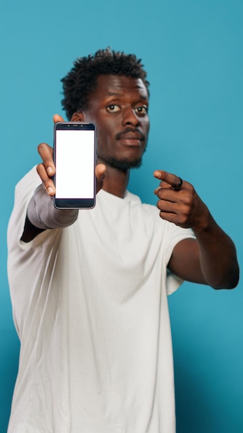 Człowiek za pomocą wyświetlacza smartfona i pokazując biały ekran do kamery w studio. Osoba wskazująca na szablon makiety i puste na białym tle na telefon komórkowy. Dorosły z kluczem chrominancji