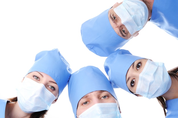 Bezpłatne zdjęcie czterech głów chirurgów w maskach tworzących razem koło