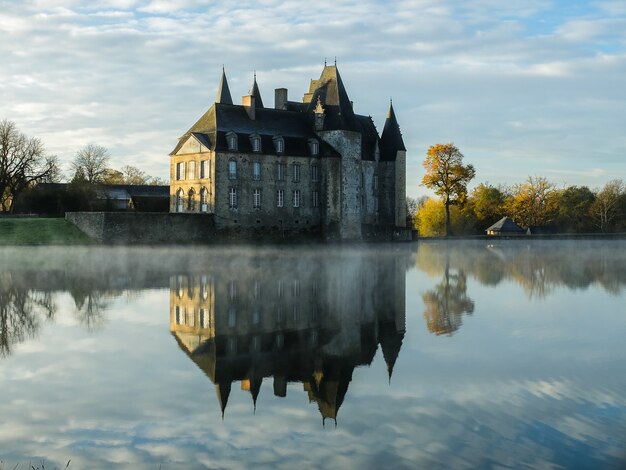 Czyste jezioro z odbiciem ogromnego zamku na tle zachmurzonego nieba jesienią