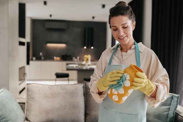 Bezpłatne zdjęcie czyszczenie naczyń. kobieta w rękawiczkach czyści pomarańczowy wazon
