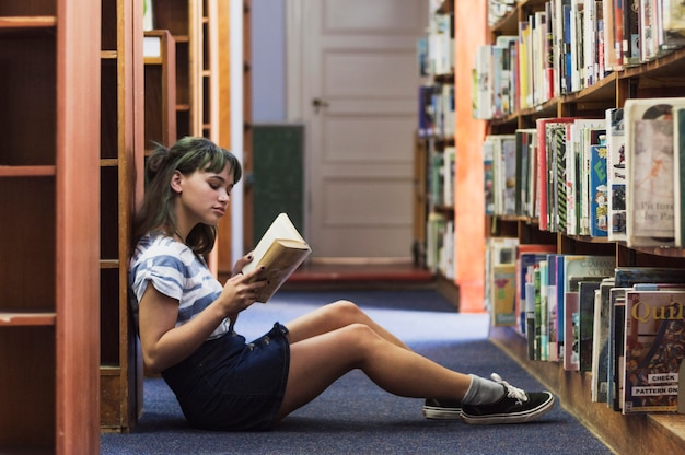 Czytanie dziewczyna siedzi na podłodze biblioteki