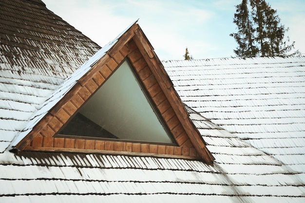 Dach drewnianego domu ze śniegiem w zimowy dzień