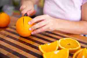 Bezpłatne zdjęcie dama trzyma nóż i tnącą pomarańcze na drewnianej desce