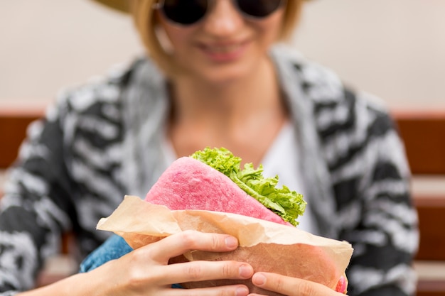 Bezpłatne zdjęcie defocused kobieta trzyma kanapkę