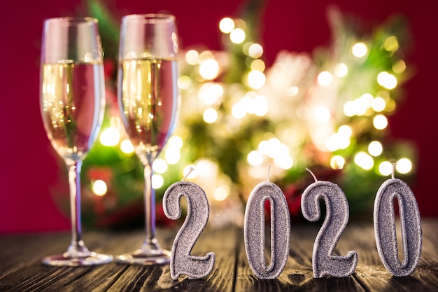 Dekoracja noworoczna. Dwa kieliszki z szampanem z dekoracją świąteczną lub noworoczną 2020 na jasnoczerwonym tle
