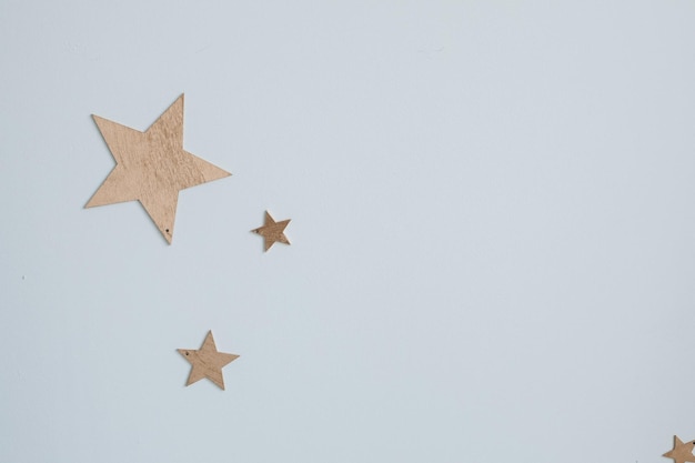 Dekoracyjne złote gwiazdki na ścianie Zbliżenie ozdobnych złotych papierowych gwiazdek różnej wielkości na gładkiej niebieskiej ścianie jak niebo