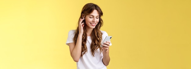 Bezpłatne zdjęcie delikatna kobieca kędzierzawa biała koszulka dotykowa bezprzewodowa wkładka douszna włożona do ucha z uśmiechem