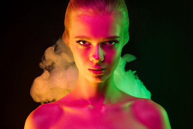 Delikatny. Portret kobiety modelka w świetle neonu w ciemności. Piękna kaukaska kobieta z modnym makijażem i zadbaną skórą