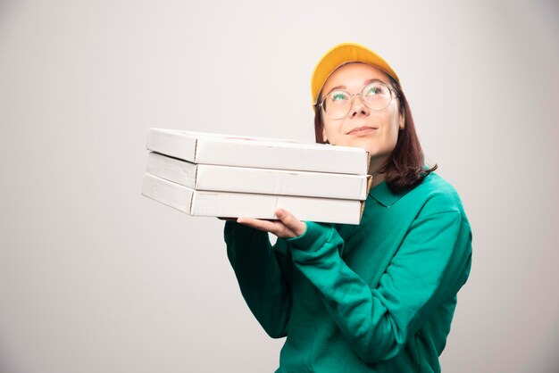 Deliverywoman niosąc kartony pizzy na białym. Zdjęcie wysokiej jakości