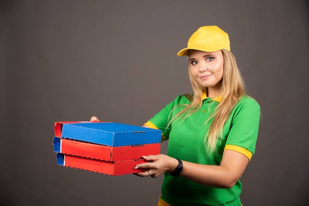 Bezpłatne zdjęcie deliverywoman w mundurze trzymając kartony pizzy.