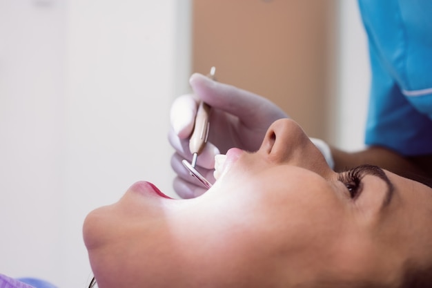 Dentysta egzamininuje żeńskiego pacjenta z narzędziami