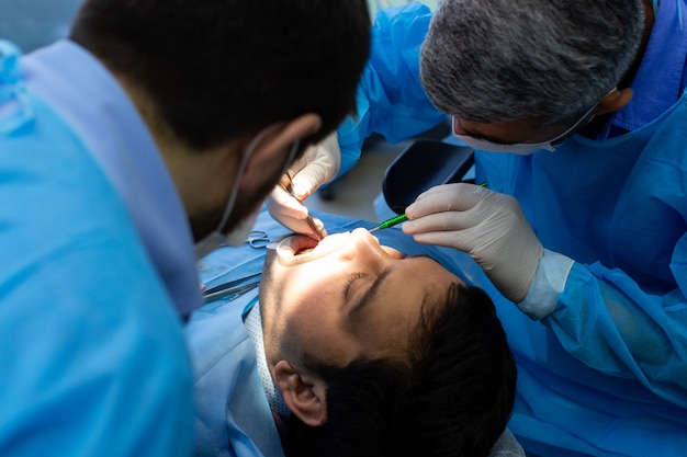 Bezpłatne zdjęcie dentysta i asystent podczas operacji w klinice dentystycznej