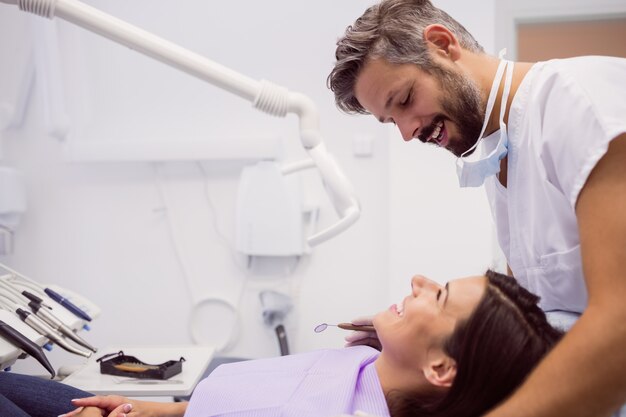 Dentysta ono uśmiecha się podczas gdy egzamininujący pacjenta