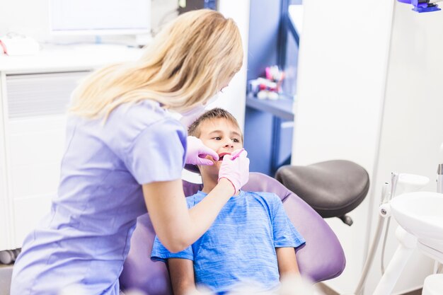 Dentysta robi stomatologicznemu traktowaniu chłopiec w klinice