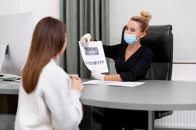 Bezpłatne zdjęcie dentysta średniego strzału wyjaśniający radiografię