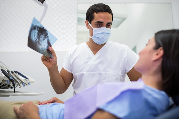 Dentysta wyjaśniający zdjęcie rentgenowskie pacjentce