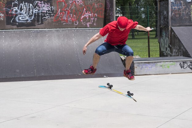 Deskorolkarz robi trik ze skokiem na tle skateparku