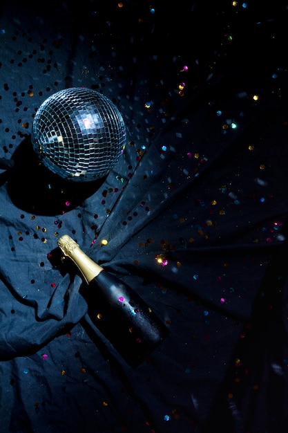 Bezpłatne zdjęcie disco ball z butelką szampana na podłodze