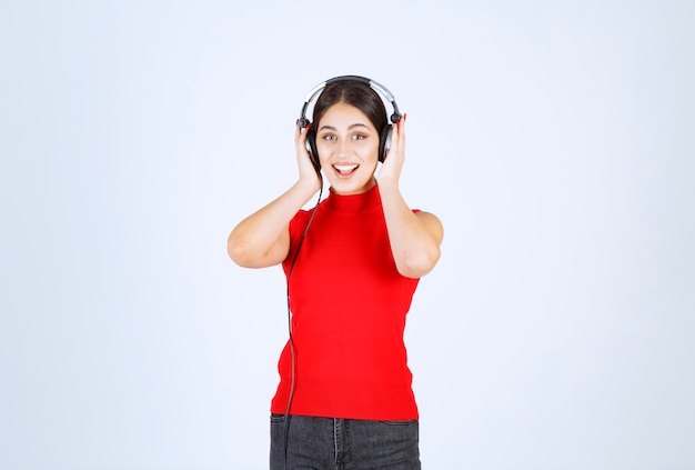 Dj dziewczyna w czerwonej koszuli na sobie słuchawki i słuchanie dobrej muzyki.