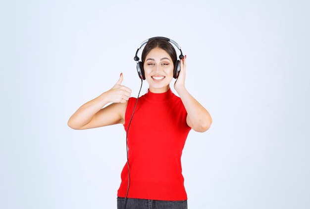 Dj w czerwonej koszuli w słuchawkach i słuchając muzyki.