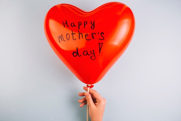 Dłoń trzymająca dzień matki balon w kształcie serca