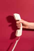 Bezpłatne zdjęcie dłoń trzymająca stary telefon z czerwonym tłem