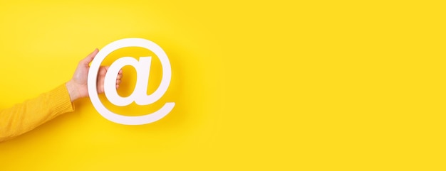 Dłoń Trzymająca Symbol E-maila Na żółtym Tle, Układ Panoramiczny Premium Zdjęcia
