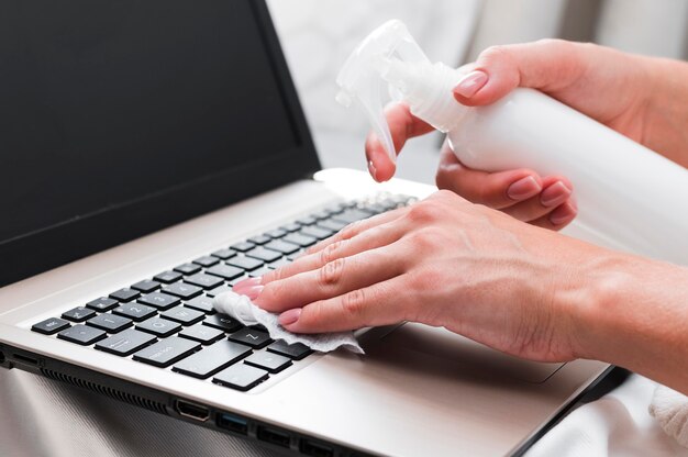 Dłonie dezynfekujące powierzchnię klawiatury laptopa