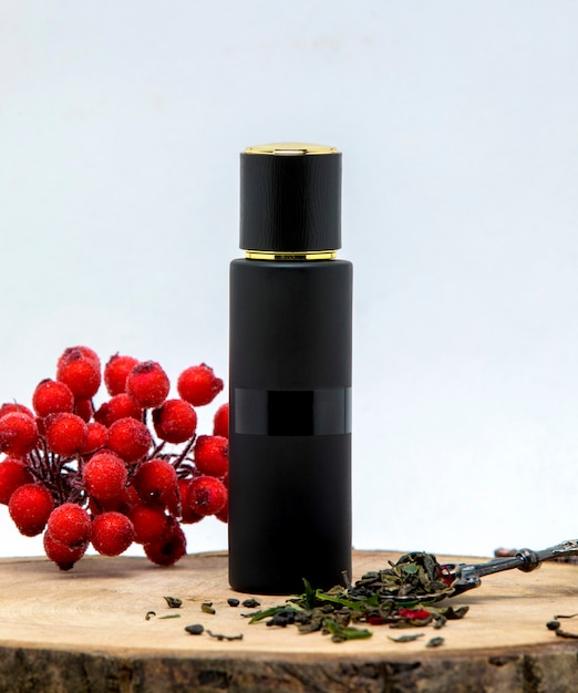 Bezpłatne zdjęcie długa czarna butelka perfum ozdobiona liśćmi żurawiny i bergamotki