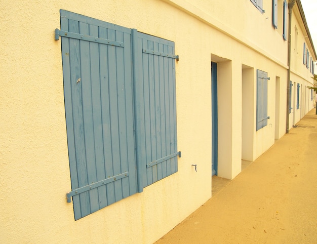 Długie ujęcie żółtej elewacji budynku z niebieskawymi wdowami i drzwiami
