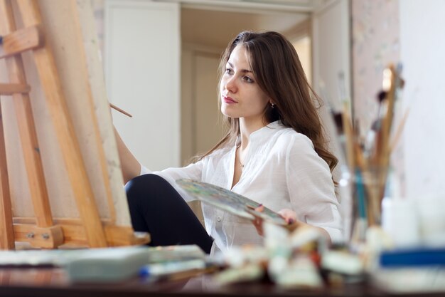 Długowłosa kobieta maluje obraz na płótnie