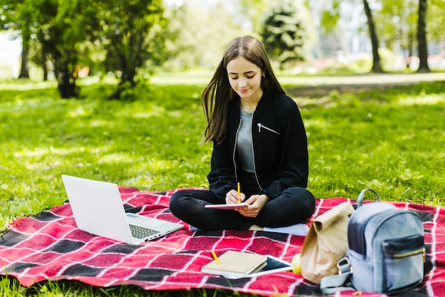 Bezpłatne zdjęcie dobra dziewczyna pisze i studiuje w parku