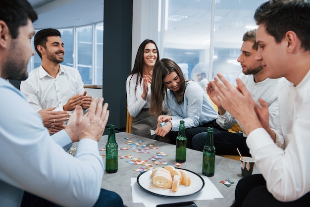 Dobry żart. świętowanie Udanej Transakcji. Młodzi Urzędnicy Siedzący Przy Stole Z Alkoholem