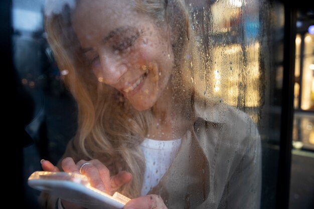 Dojrzała kobieta pisze przez telefon podczas deszczu