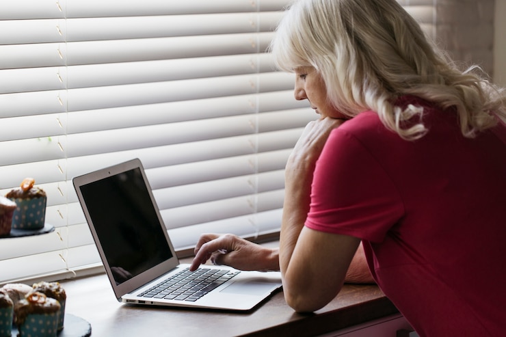 Bezpłatny plik Zdjęcie dojrzała kobieta używa laptop blisko okno