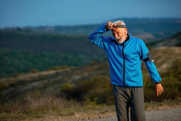 Dojrzały, wysportowany mężczyzna czuje się wyczerpany po porannym joggingu w naturze