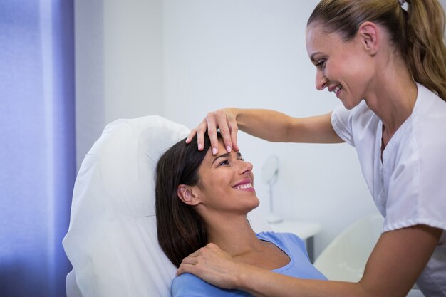 Doktorska egzamininuje żeńska pacjent twarz przy kliniką