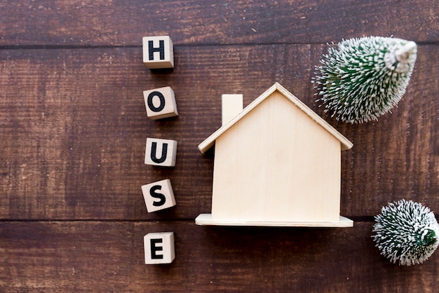 Bezpłatne zdjęcie dom list bloki w pobliżu model nieruchomości z dwoma choinki na drewniane teksturowanej tło
