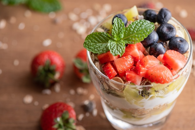 Domowe musli, miska musli owsianej z jogurtem, świeżymi jagodami, morwą, truskawkami, kiwi, miętą i orzechami na zdrowe śniadanie, miejsce. Koncepcja zdrowego śniadania. Czyste jedzenie.